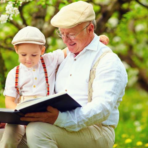 Na zdjęciu widać dziadka z wnukiem czytających książkę