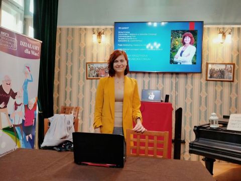 Angelika Kruszynska na zdjęciu kobieta przy komputerze w sali konferencyjnej.