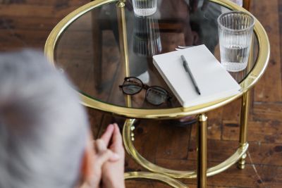 Na zdjęciu w pokoju dwie osoby podczas rozmowy przy stoliku szklanym.