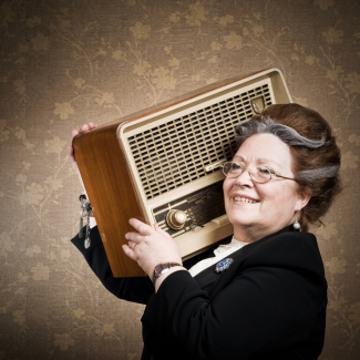 Na zdjęciu widać seniorkę trzymającą radio