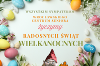 Kartka Wielkanocna. Jajka kolorowe ułożone na stole w wieniec przeplatany kwiatami na froncie krasnal z liściem dębu. 