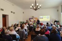 W sali konferencyjnej ludzie siędzący na krzesłach i wręczanie nagród. 