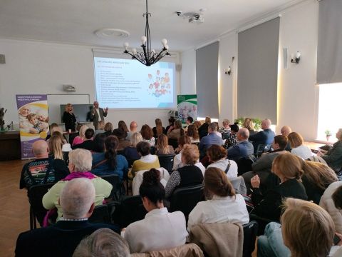 Na zdjęciu w sali konferencyjnej siedzące osoby na krzesłach podczas prezentacji Dni Seniora 2025. 