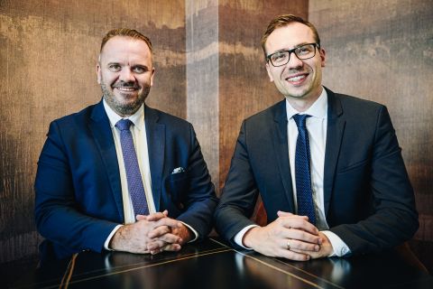 Na zdjęciu dwóch mężczyzn siedzących przy stole.  