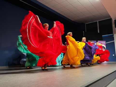 Tańczące seniorki w długich, kolorowych sukniach.