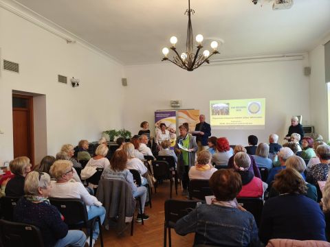 W sali konferencyjnej ludzie siędzący na krzesłach i wręczanie nagród. 