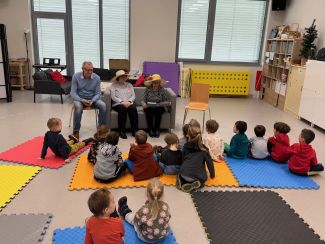 Seniorzy czytający książki dla dzieci w bibliotece.