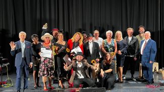 Grupa laureatów  z muzykami na scenie podczas II Senioralnego Przeglądu Piosenki Artystycznej.