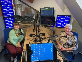 Dwie panie przy stole przy mikrofonach w studiu radiowym.