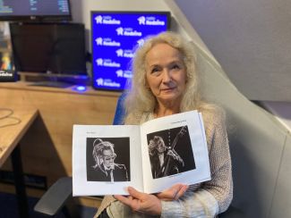 Fotografia na której jest Krystyna Ewa Kubacka ze zdjeciami w studiu Radia Rodzina.