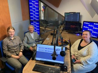 Na zdjęciu trzy panie w różnym wieku siedzące w studiu radiowym radia rodzina.