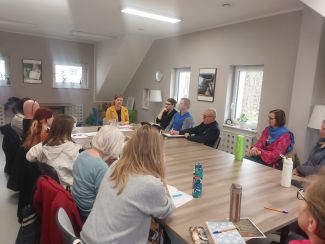 Grupa ludzi przy stołach w pokoju.