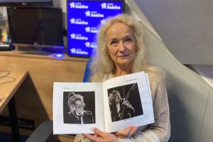 Fotografia na której jest Krystyna Ewa Kubacka ze zdjeciami w studiu Radia Rodzina.
