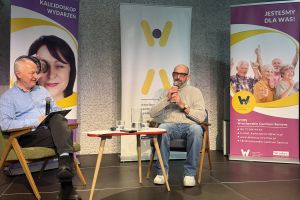 Stanisław Dzierniejko i Janusz Chabior siedzą na krzesłach na scenie.