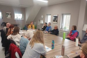 Grupa ludzi przy stołach w pokoju.