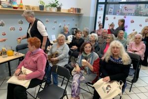 Seniorzy siedzący na krzesłach w centrum.